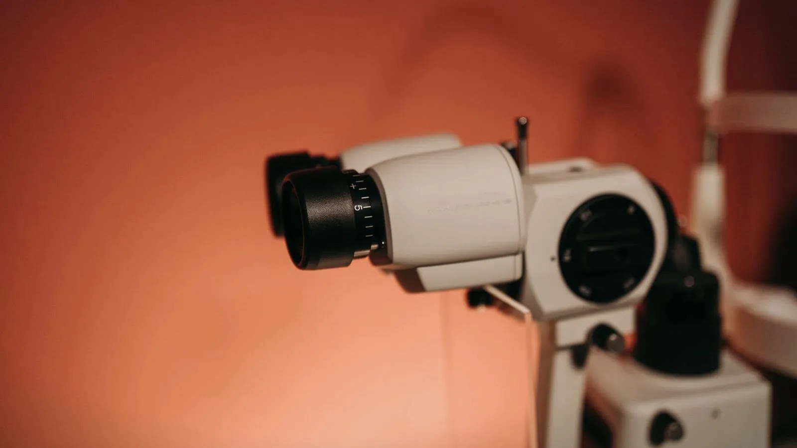 An eye examination camera against a warm orange wall