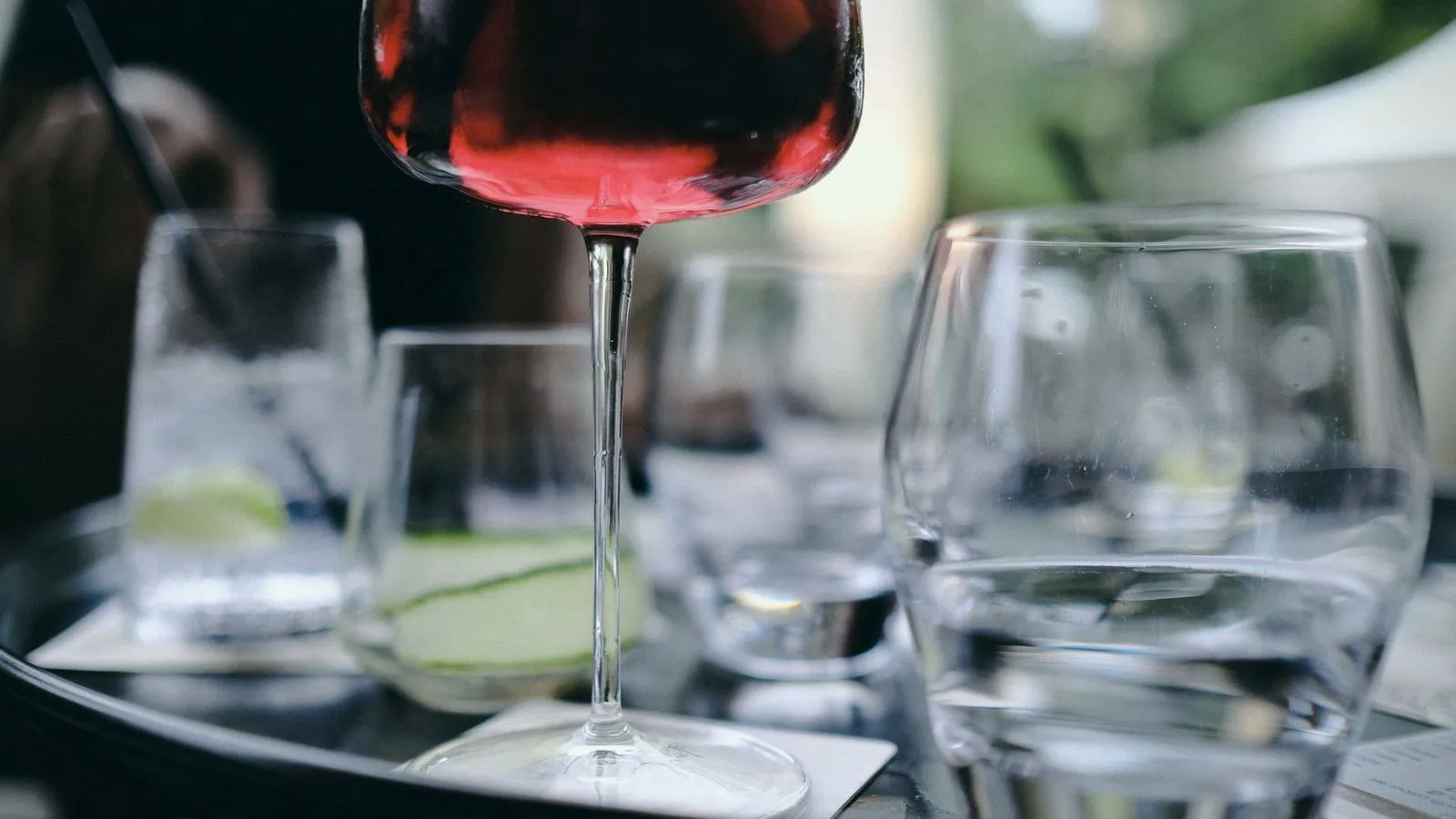 A glass of red wine on a cafe table beside water glasses