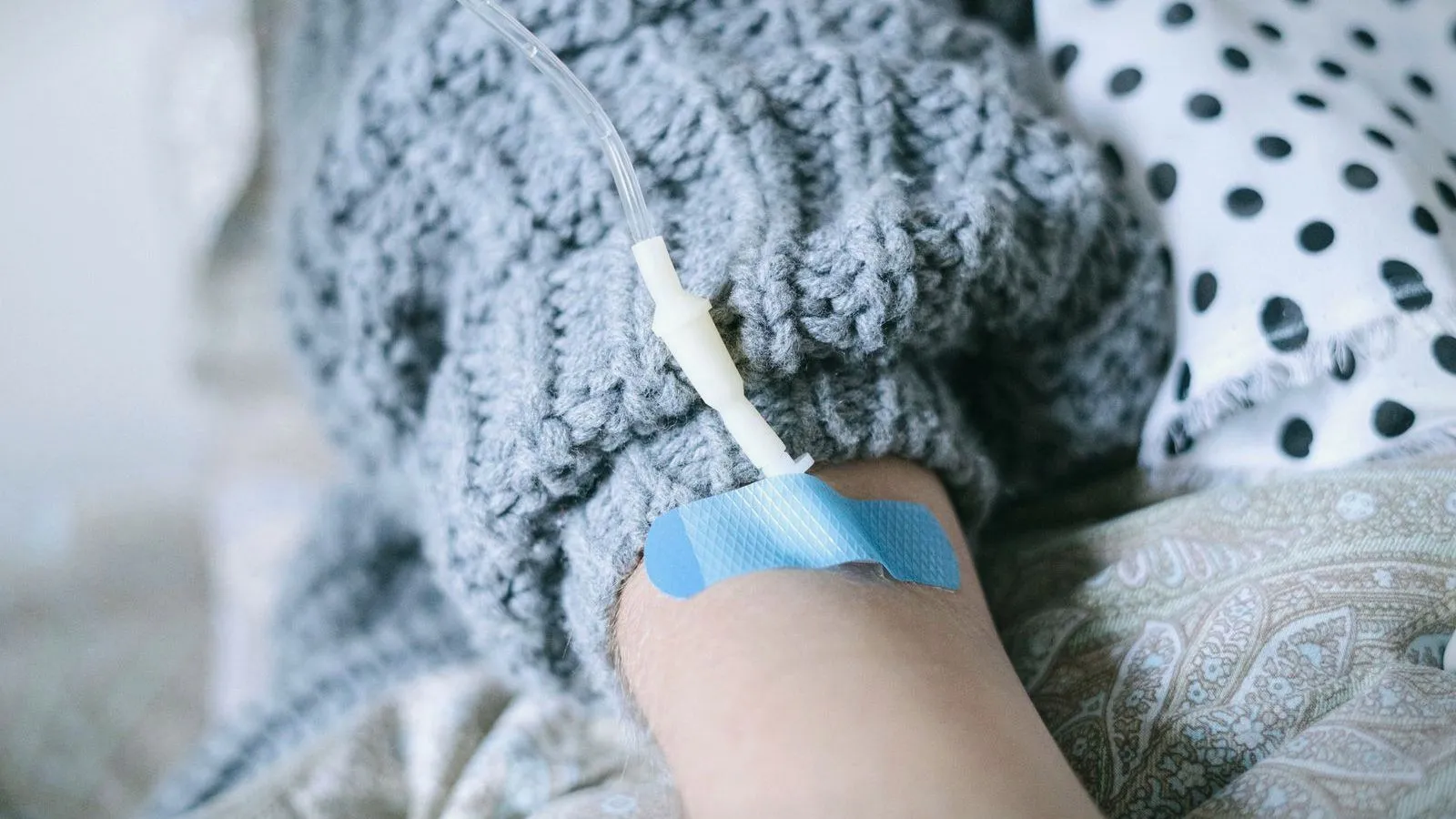 A forearm with a cannula and drip line taped in place
