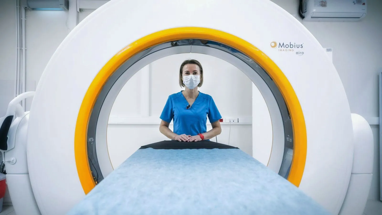 A radiographer standing behind the open bore of a scanner