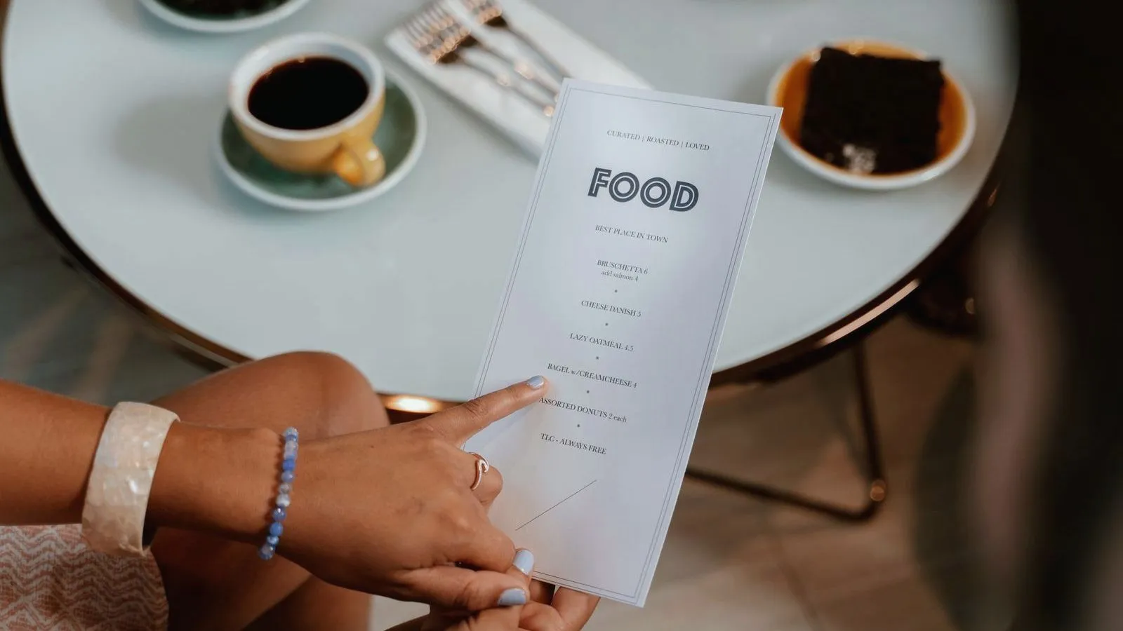 A person holding a printed cafe menu at a table