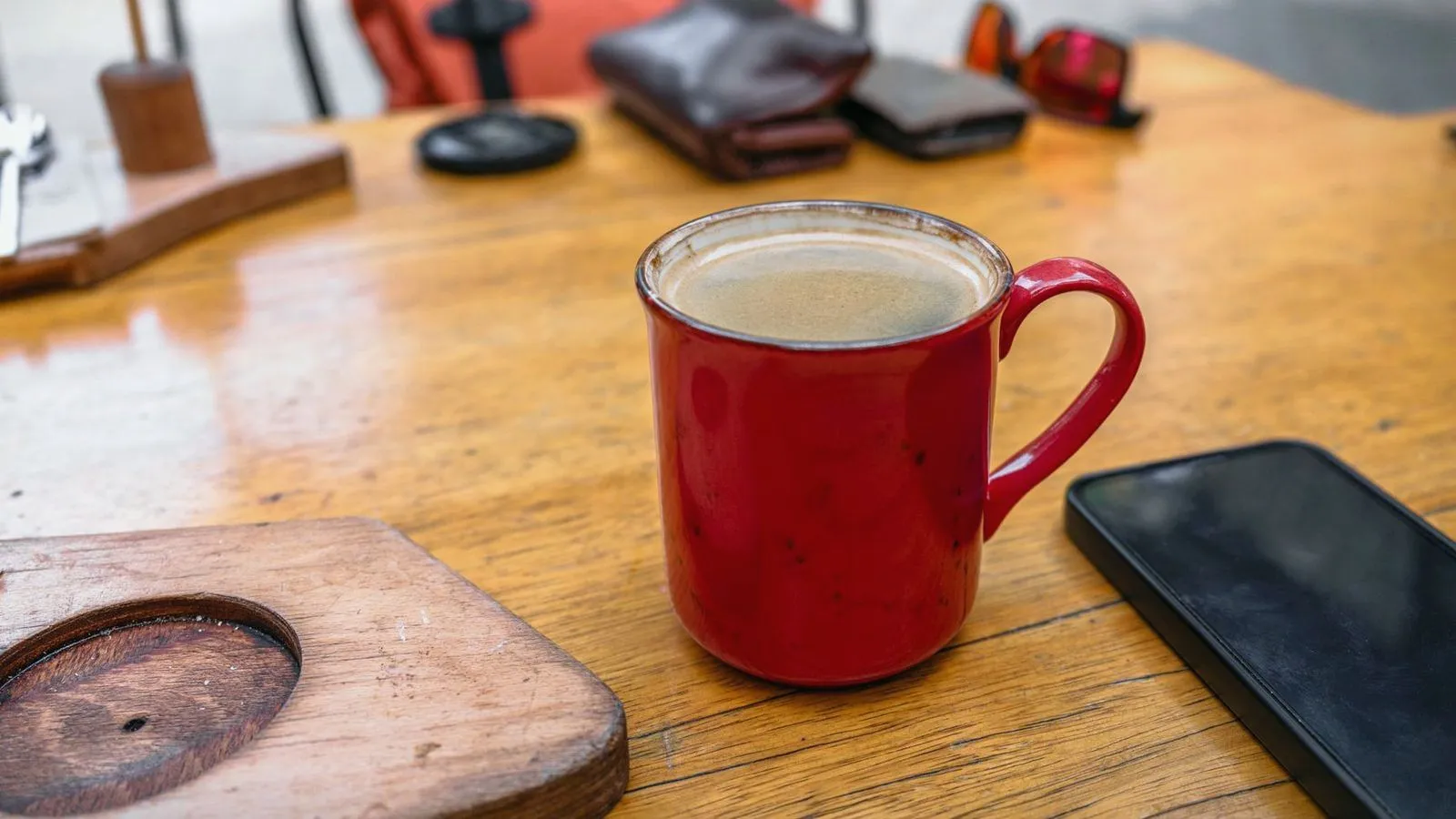 A red mug of black coffee on a wooden cafe table