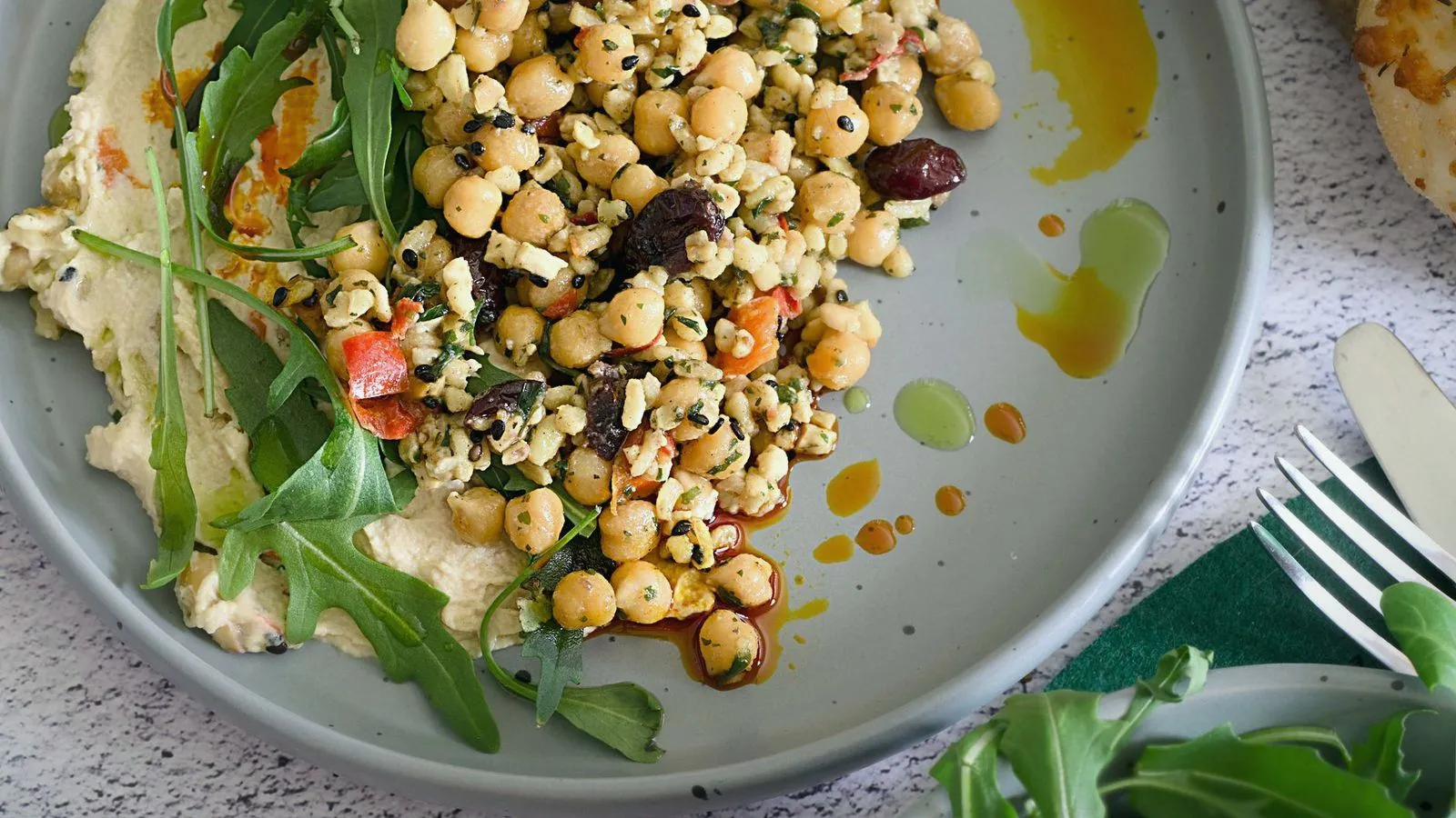 A plate of chickpea salad with hummus, rocket leaves and olive oil