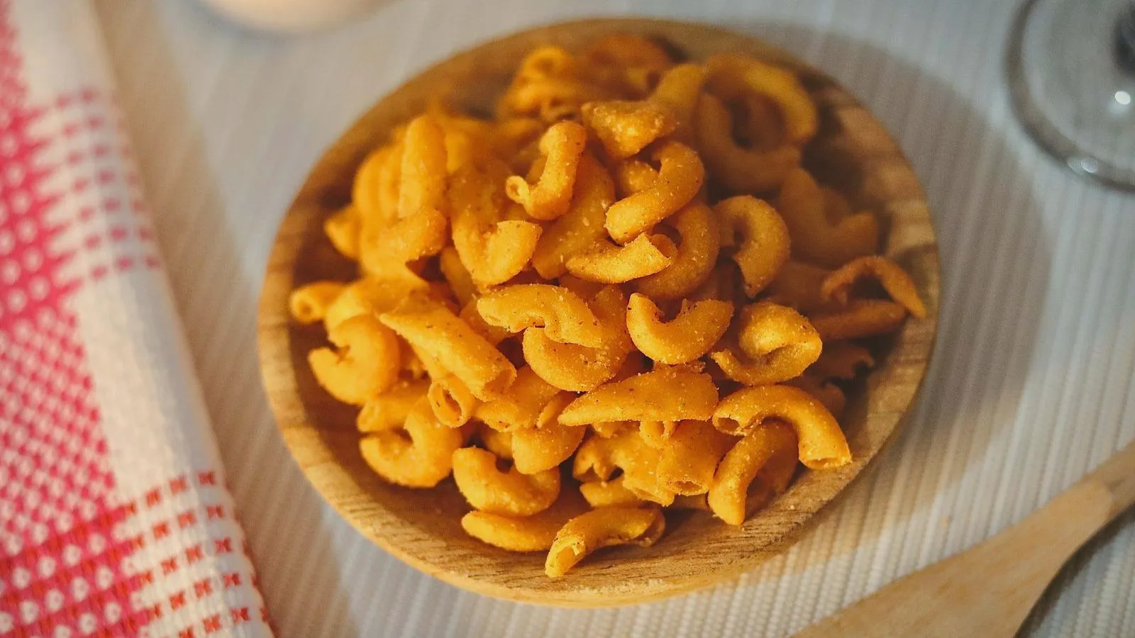 A wooden bowl of fried snack curls on a table