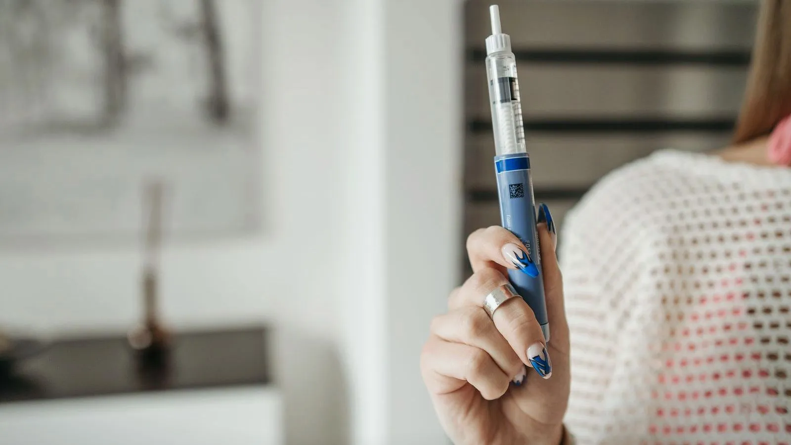 A person holding a blue medical injection pen indoors