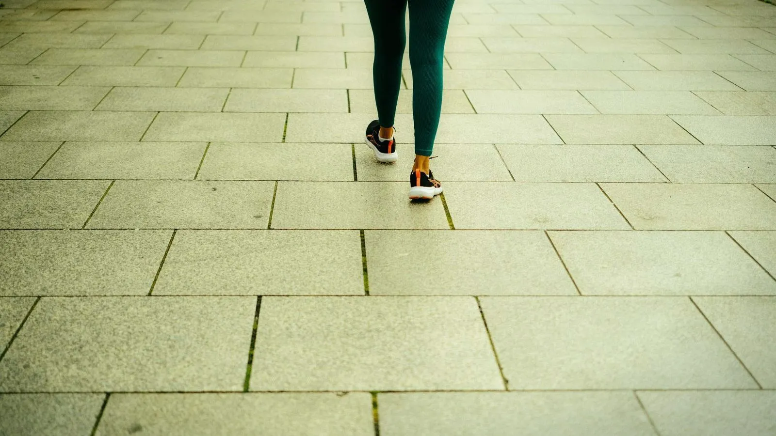 A close-up of legs walking briskly across paving stones