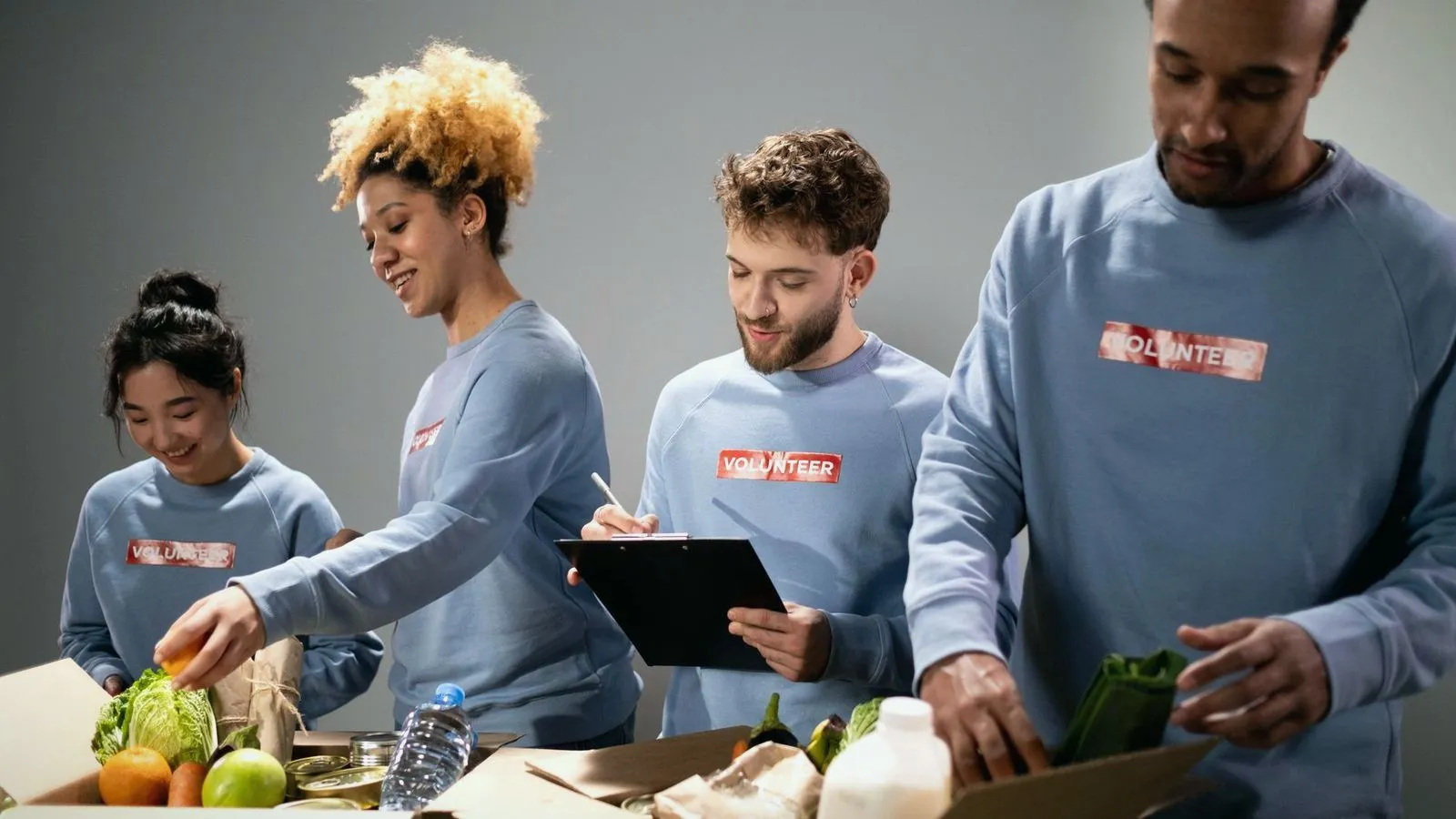 Volunteers in matching sweatshirts packing boxes of fresh food