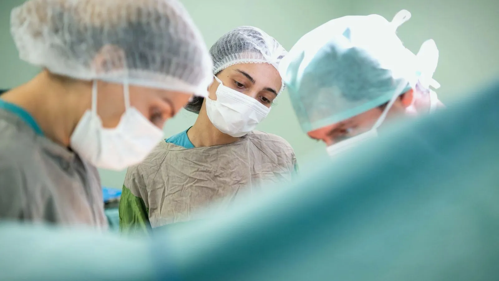 Masked surgeons working under theatre lights during an operation