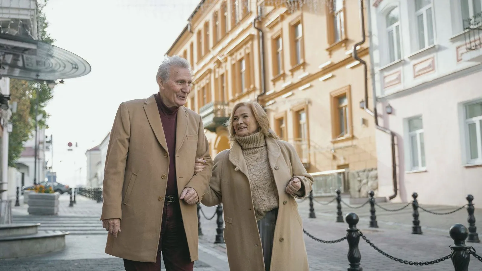 An older couple walking arm in arm along a city street