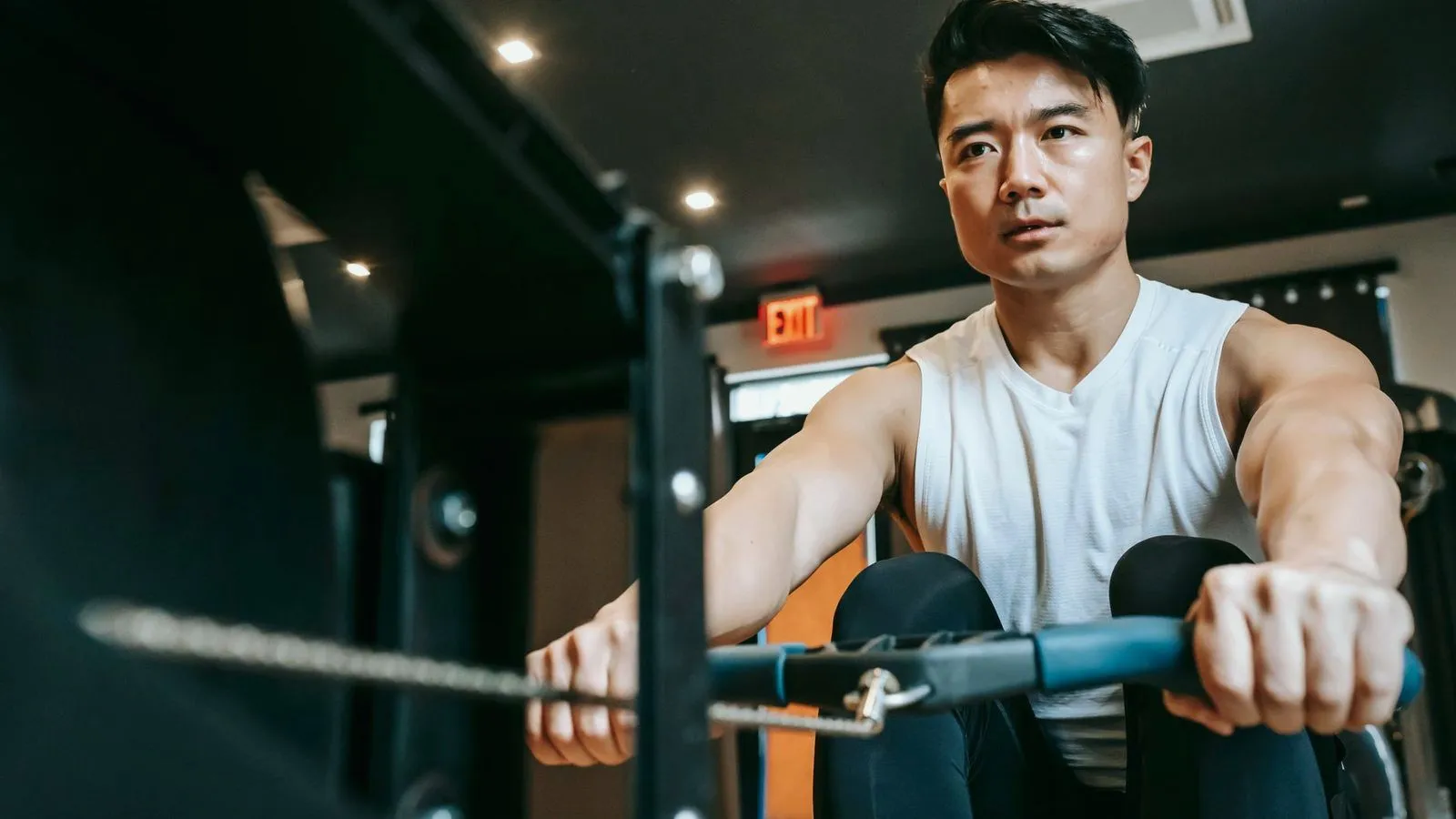 A man pulling hard on the handle of a rowing machine in a gym