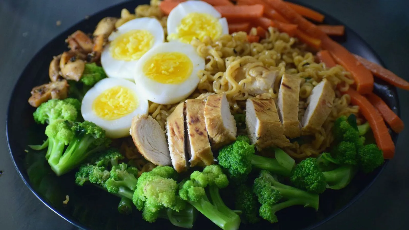 A plate of sliced chicken, boiled eggs, broccoli and carrots