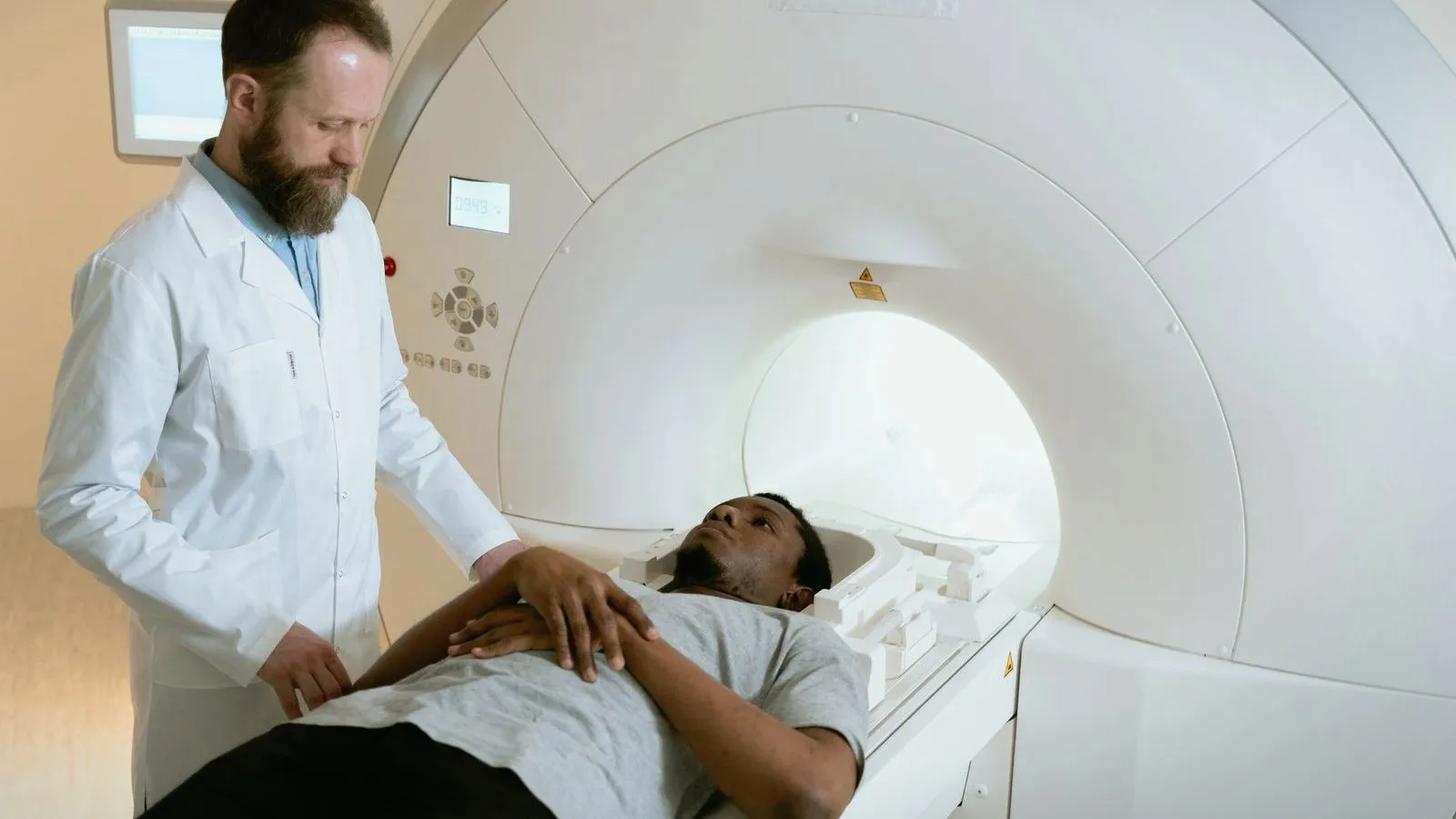 A radiographer positioning a patient at the mouth of an MRI scanner