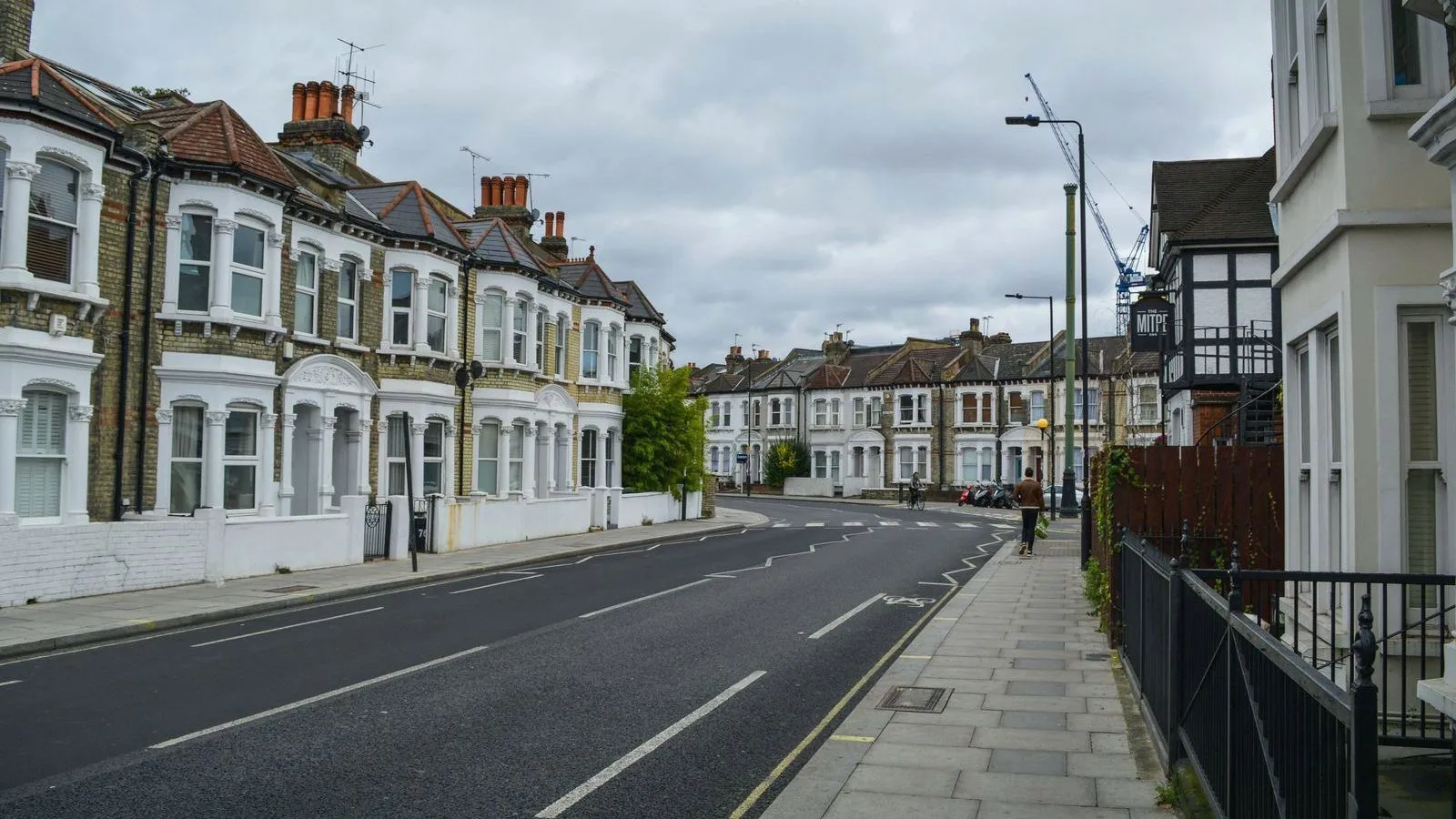 An empty residential street lined with terraced houses under a grey sky