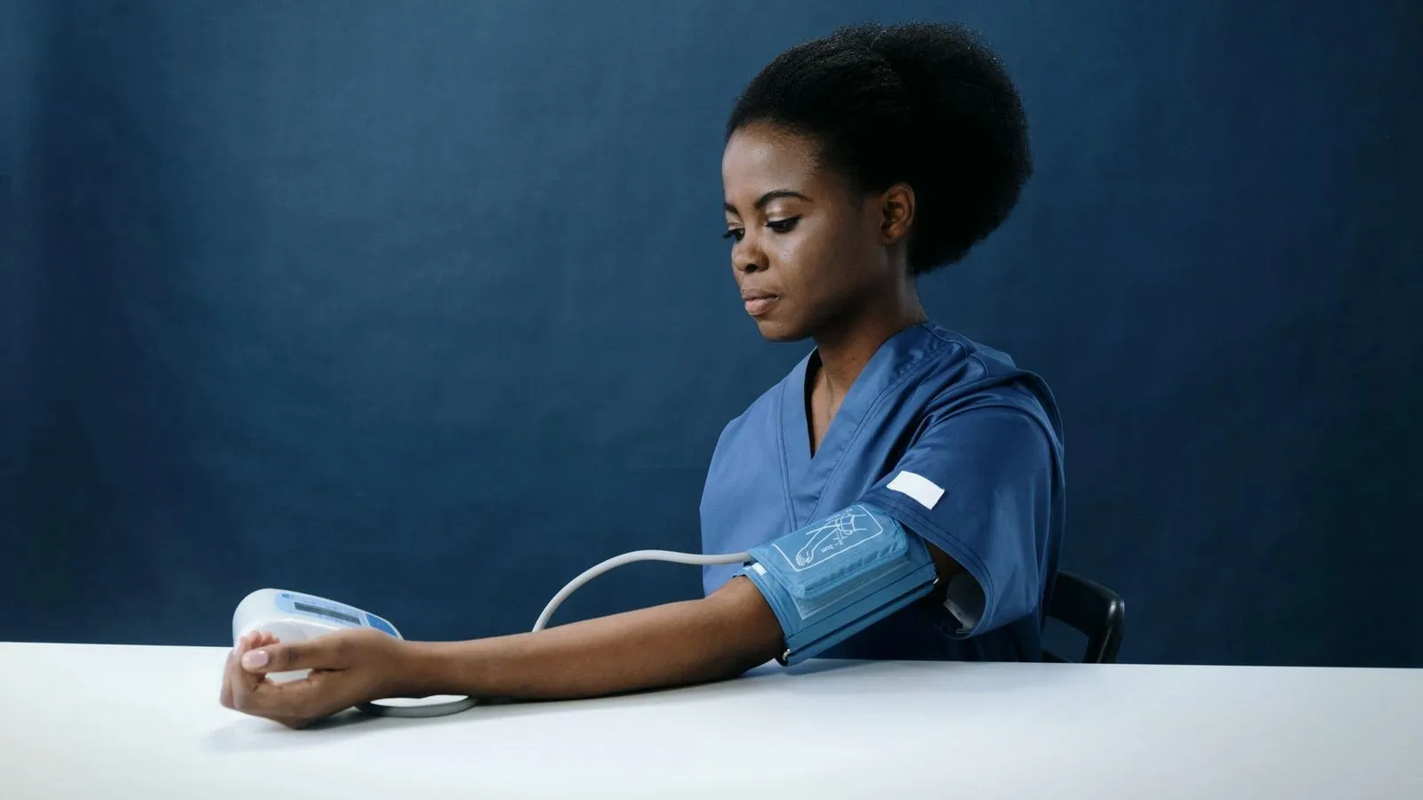 A healthcare worker measuring her blood pressure with an arm cuff