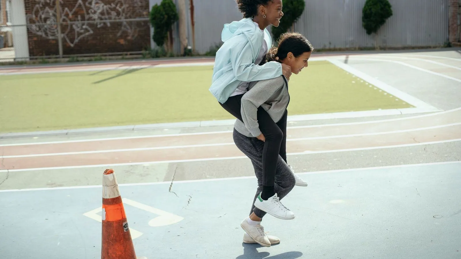 Two teenagers playing on an outdoor running track