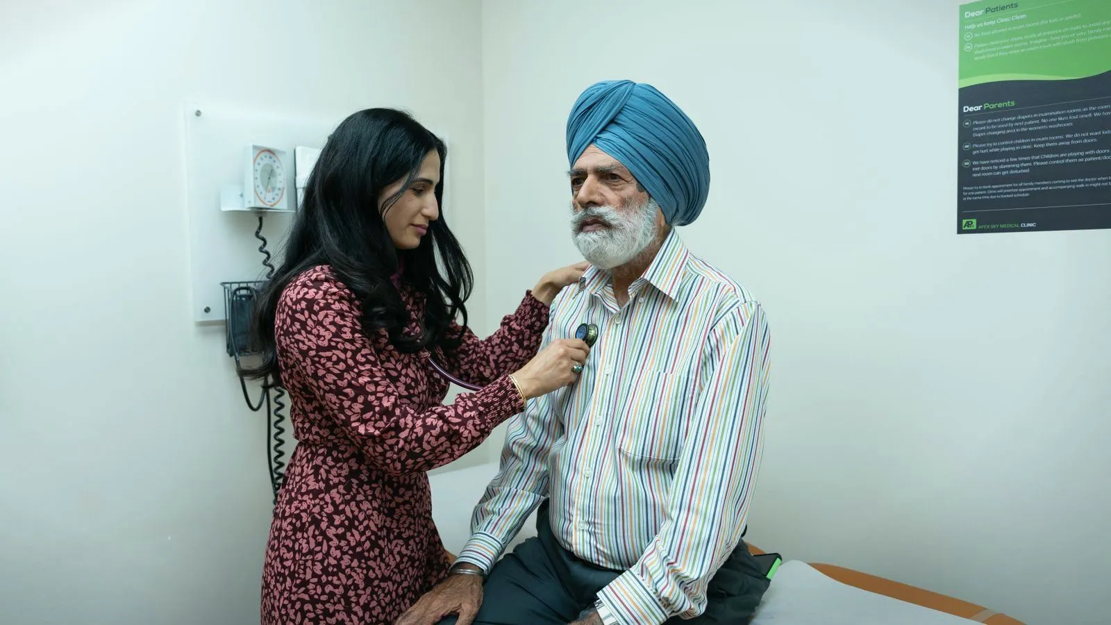 A doctor listening to an older patient's chest with a stethoscope in a clinic room