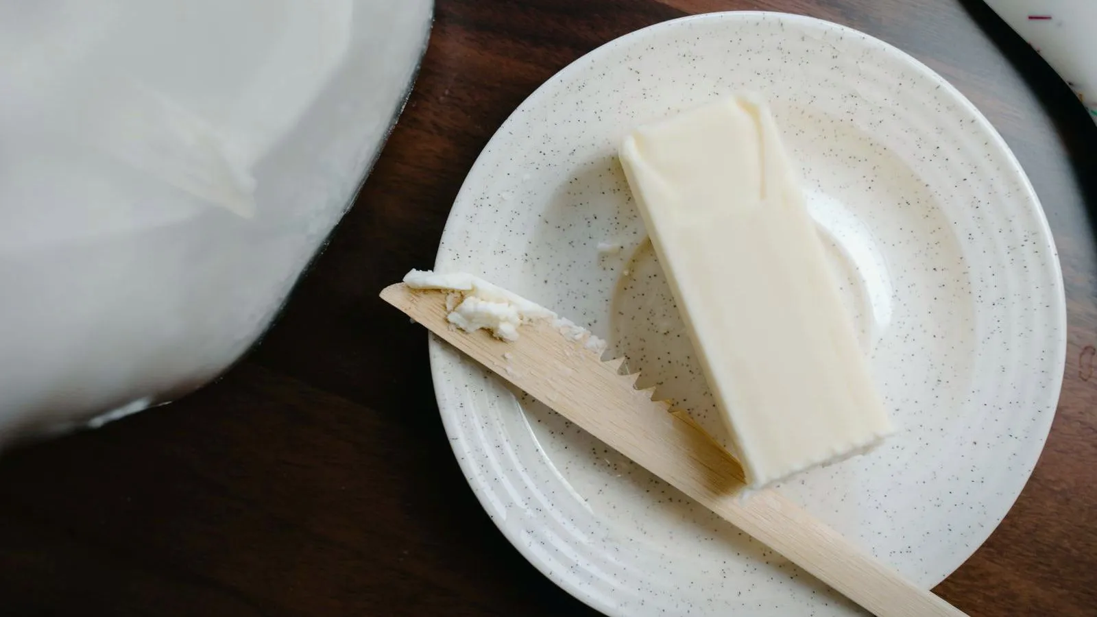 A block of butter and a wooden knife on a ceramic plate