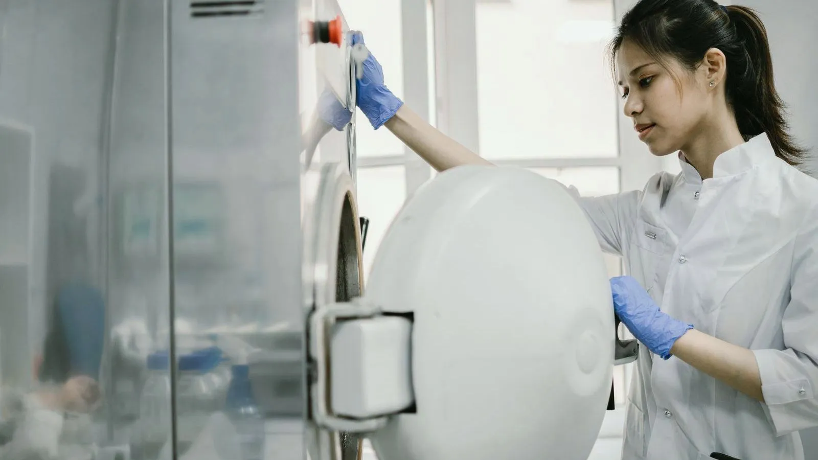 A researcher in a white coat loading a sample into a laboratory centrifuge
