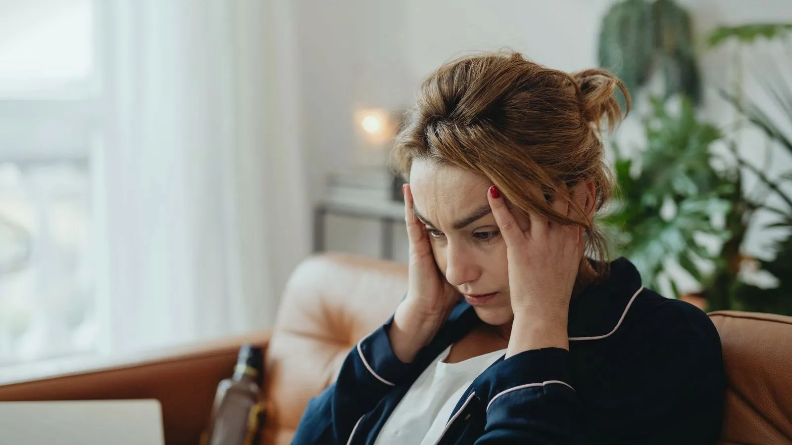 A woman on a sofa pressing her fingers to her temples