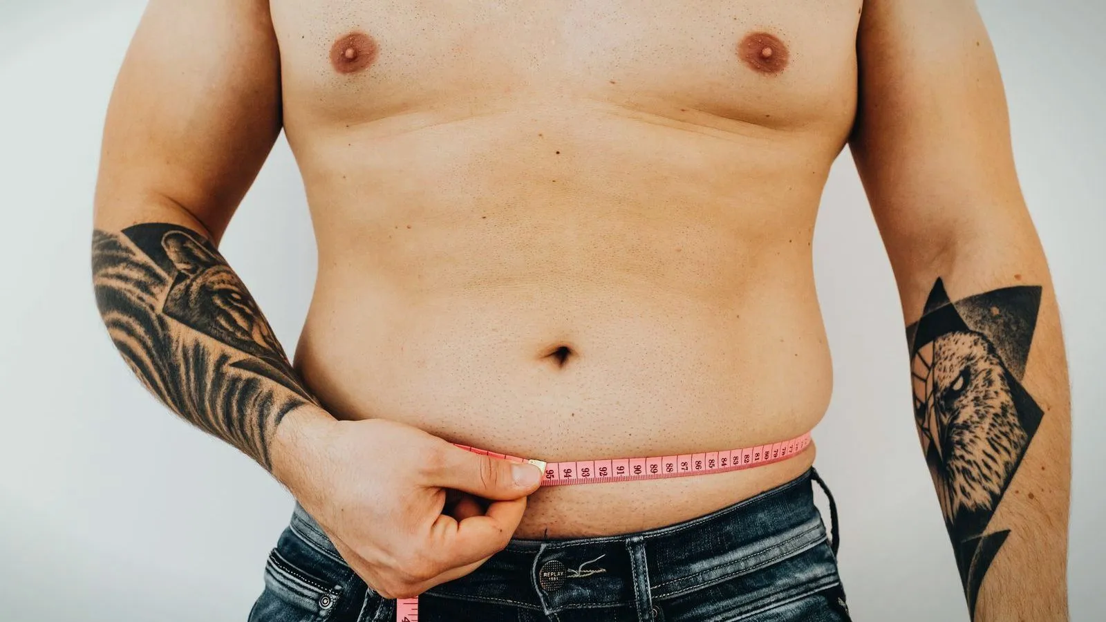 A man measuring his waist with a tape measure