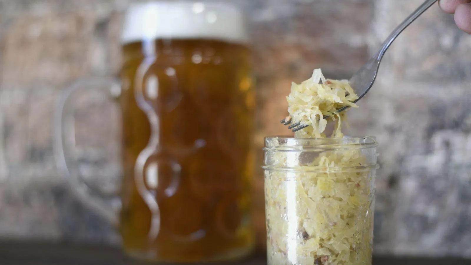 A glass jar of sauerkraut with a fork lifting out a forkful