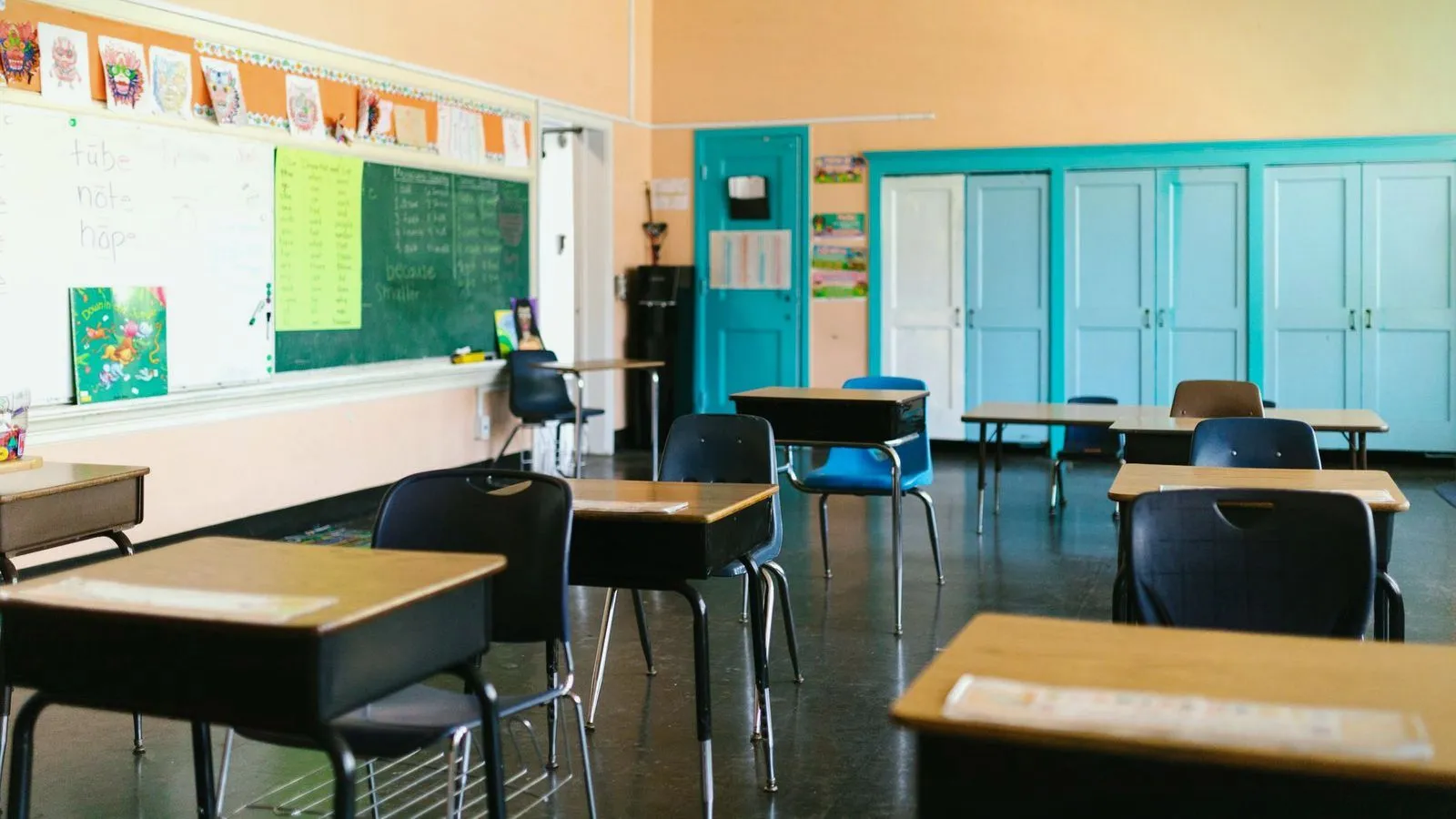 An empty classroom of desks facing a chalkboard