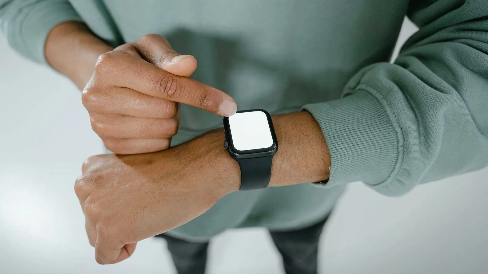 A person tapping a blank-screened smartwatch worn on their wrist