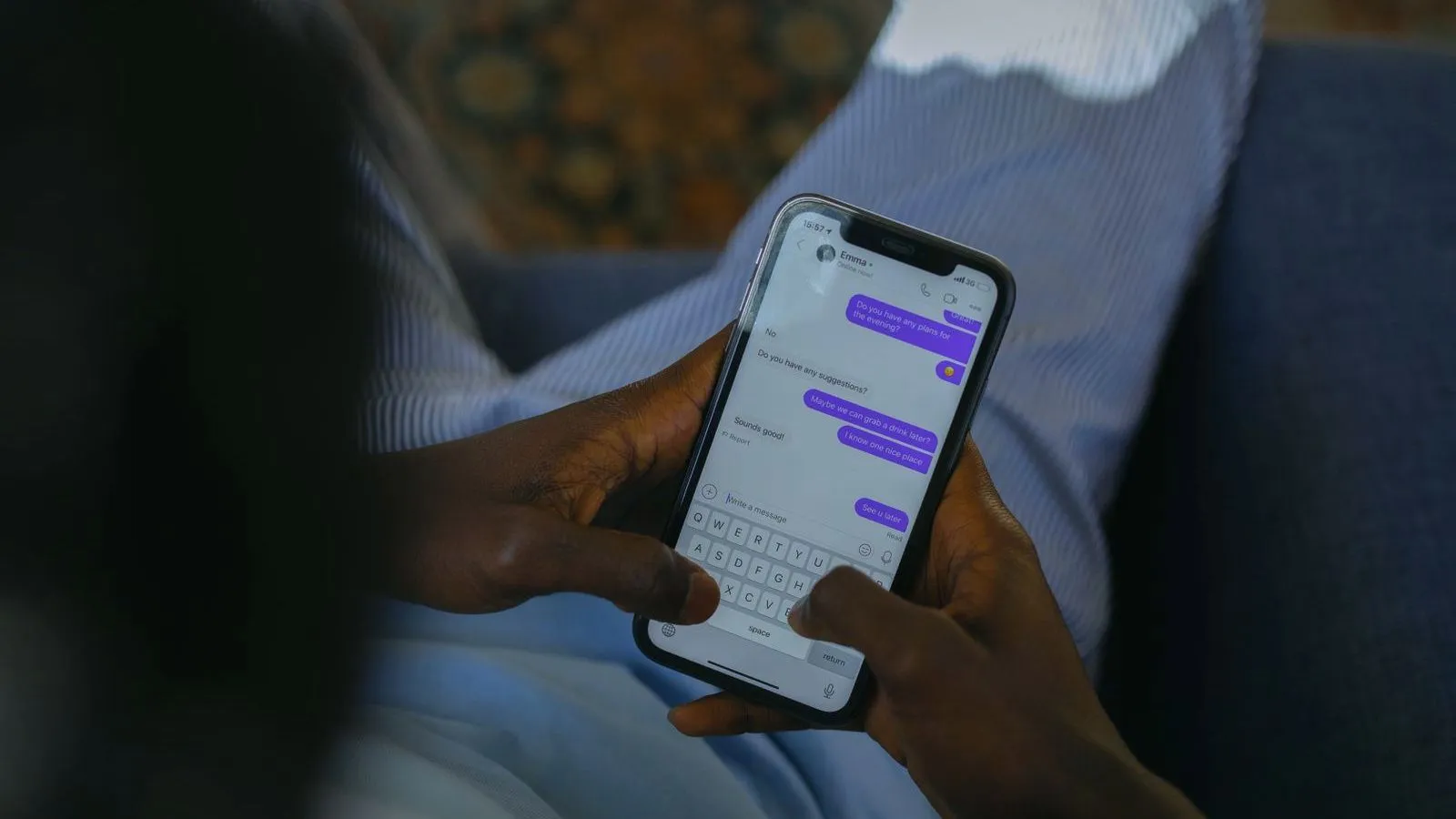 Hands typing a message on a phone showing a thread of chat bubbles