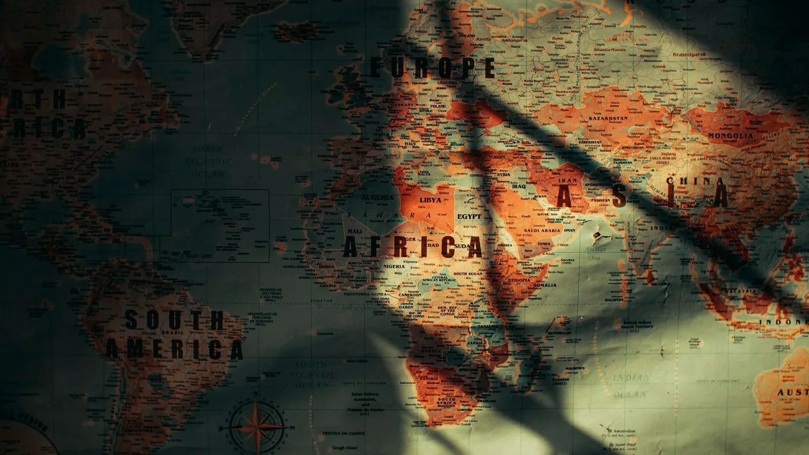 An aged paper world map in shadow, with Africa and South America labeled