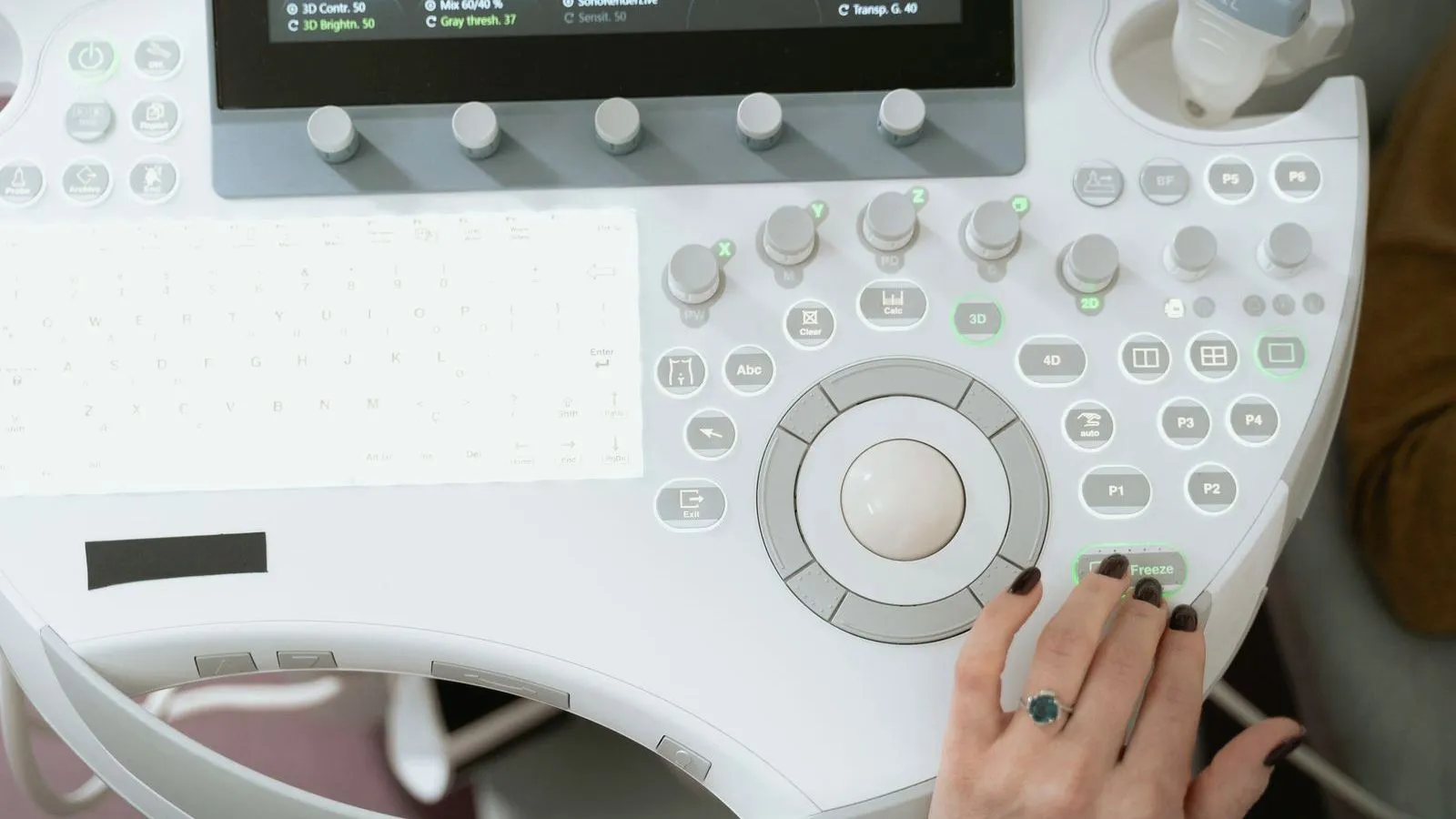 A hand operating the control panel of an ultrasound scanner