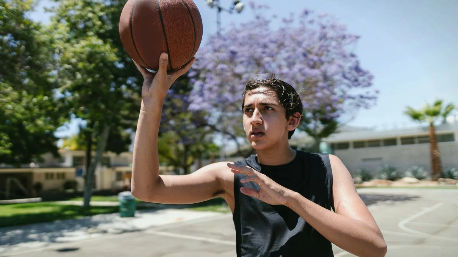 A teenager lining up a shot with a basketball on an outdoor court