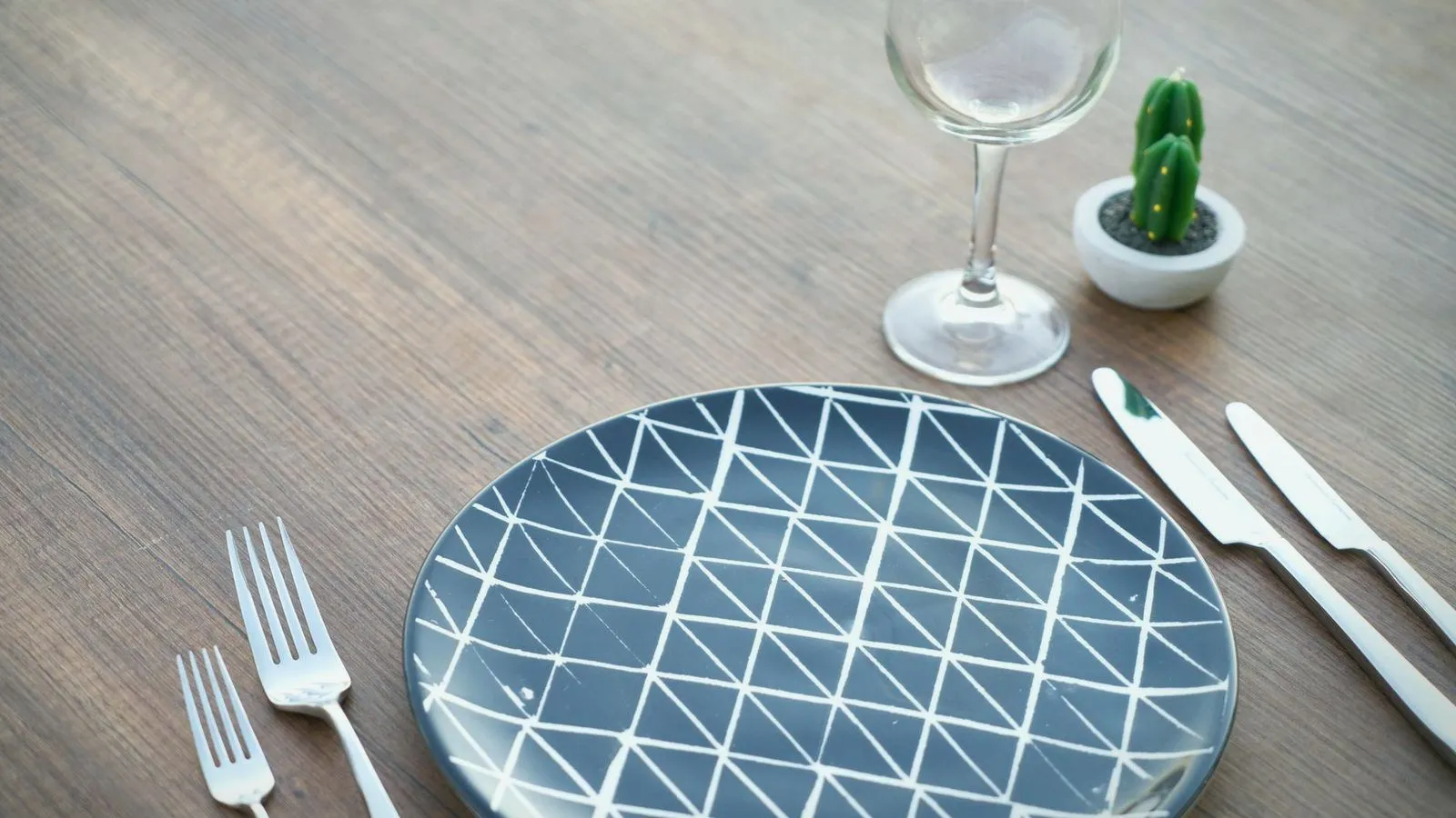 An empty plate and cutlery set out on a wooden table