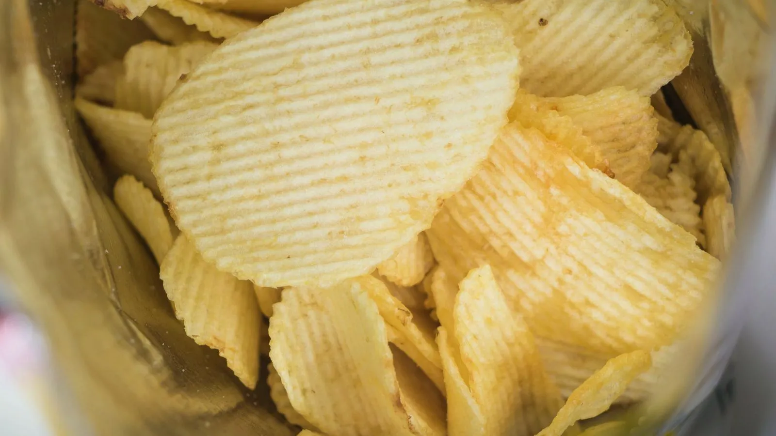 A close-up of ridged potato chips inside an open snack bag