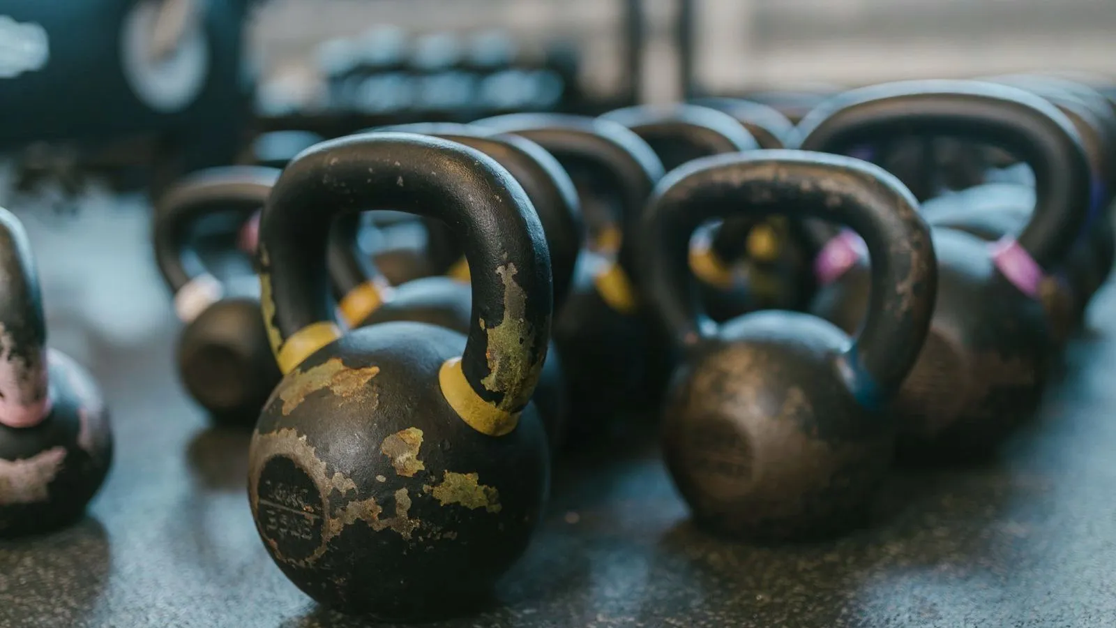 A row of worn kettlebells lined up on a gym floor