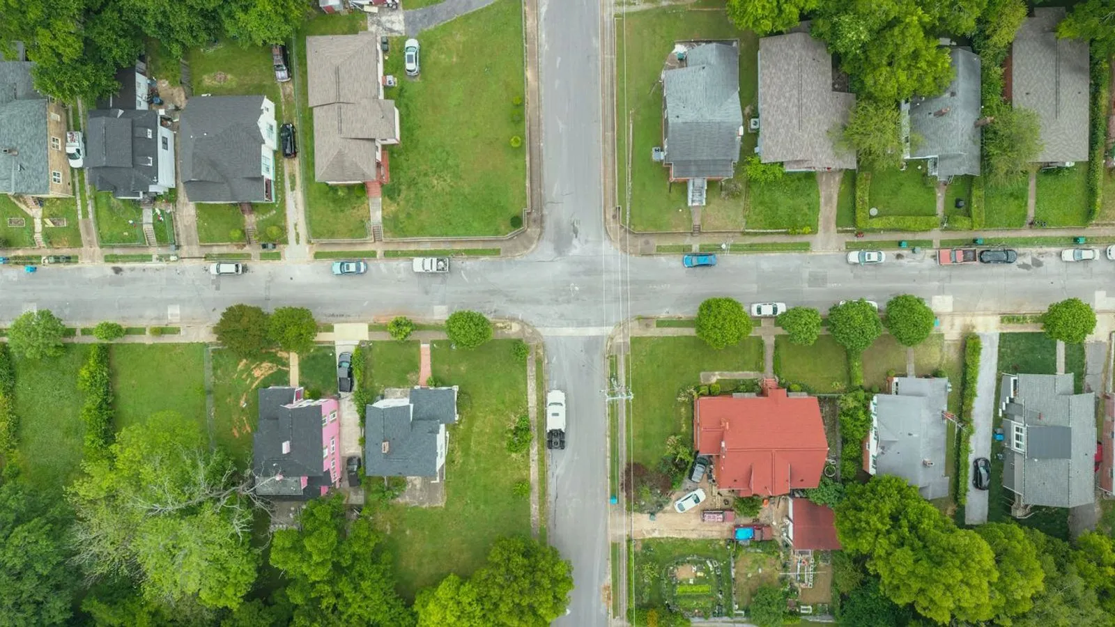 An overhead view of a residential street crossing with houses and gardens
